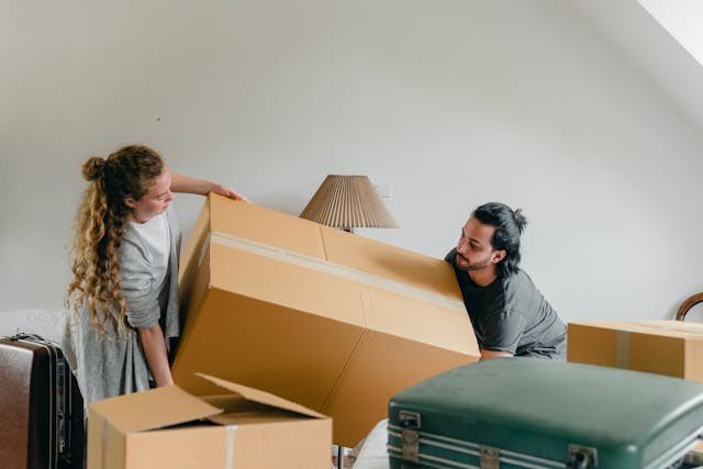 Couple moving a heavy box after discussing how to safely move your hunting gear.