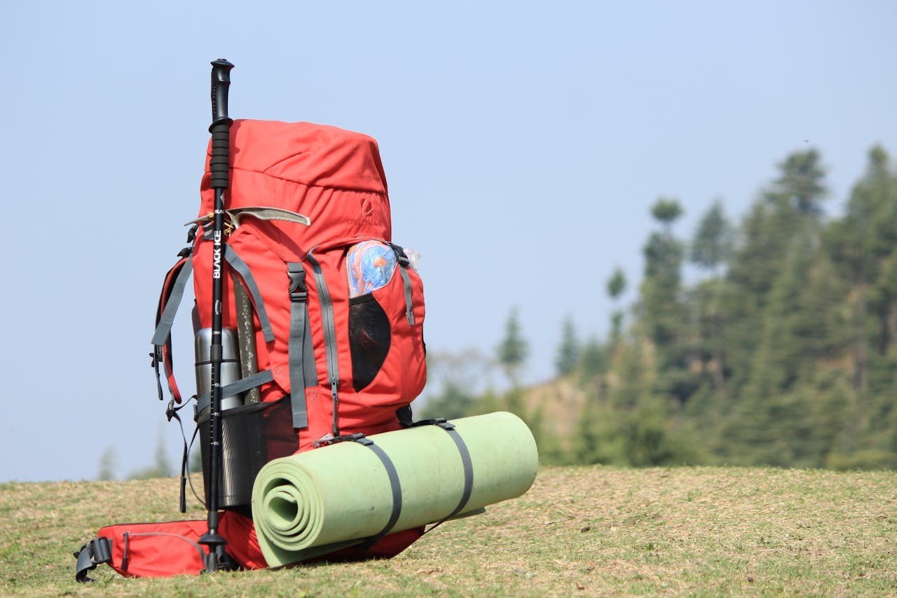 A red backpack in the middle of green grass.